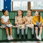 Four girls sitting indoors reading books, fostering a love for learning and education.